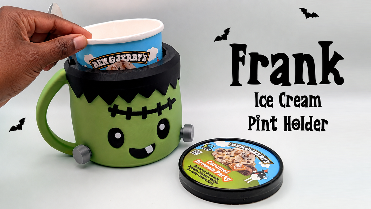 Green Frankenstein-inspired ice cream pint holder with black hair, stitched forehead, silver bolts and handle, shown with a pint tub