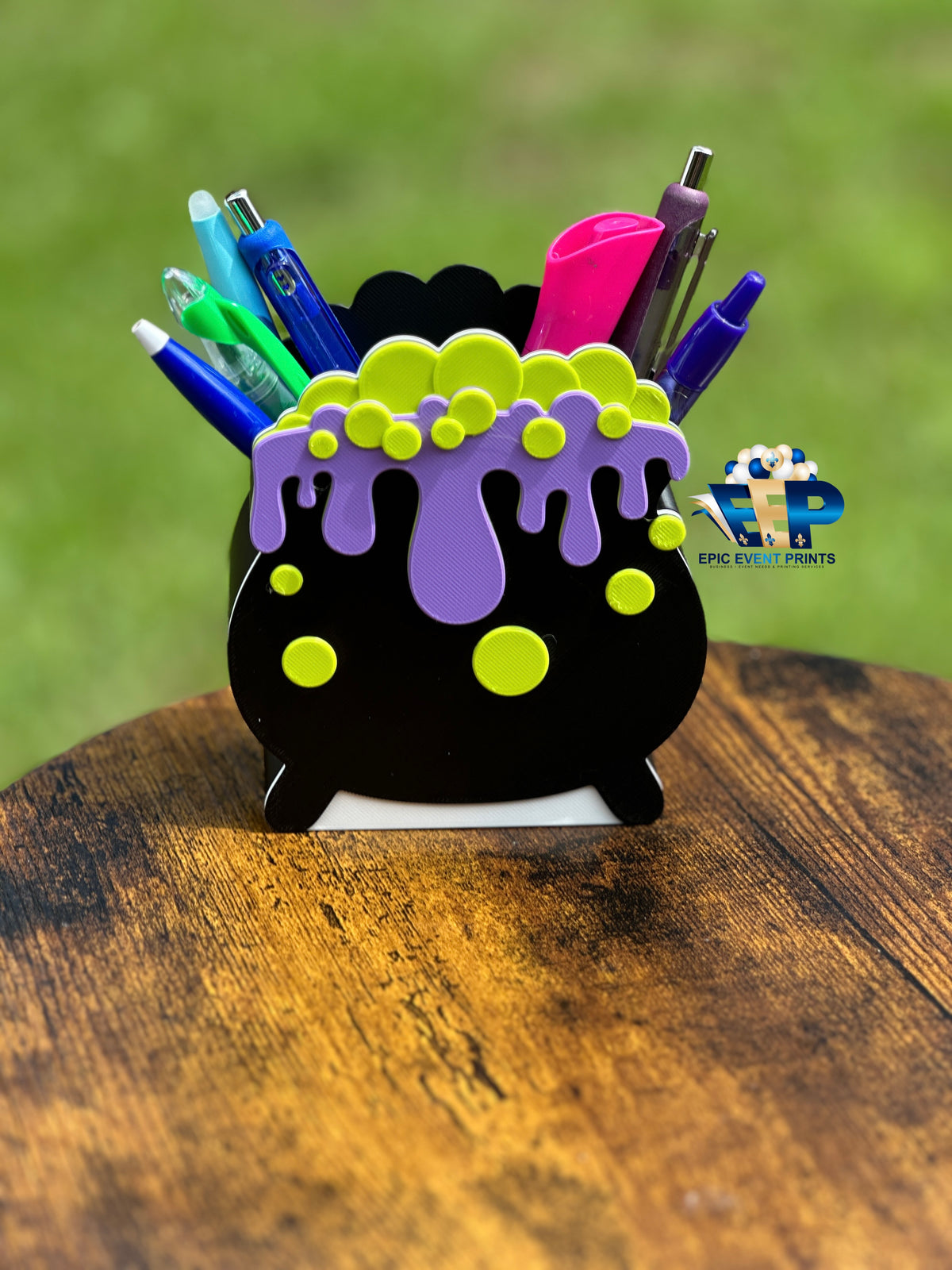 Black cauldron badge reel with purple drips and green bubbles