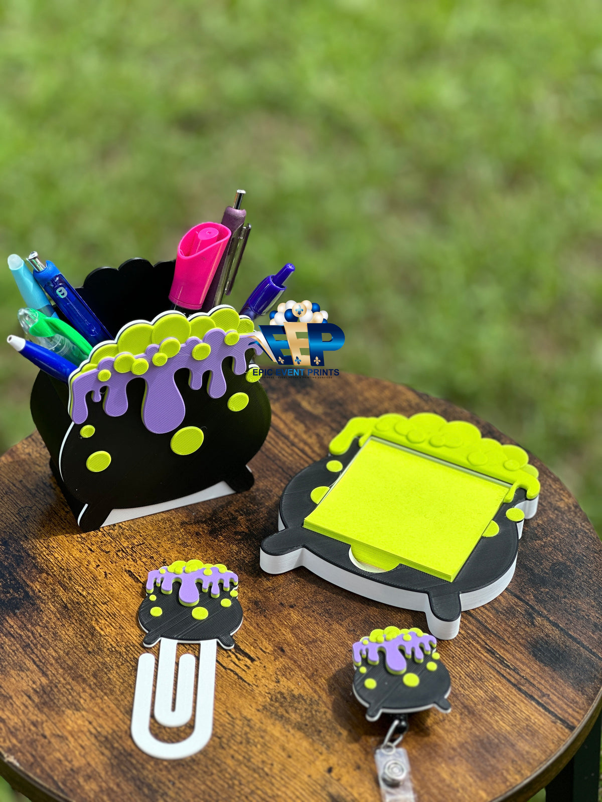 Black cauldron with purple drips and green bubbles attached to a white paper clip bookmark