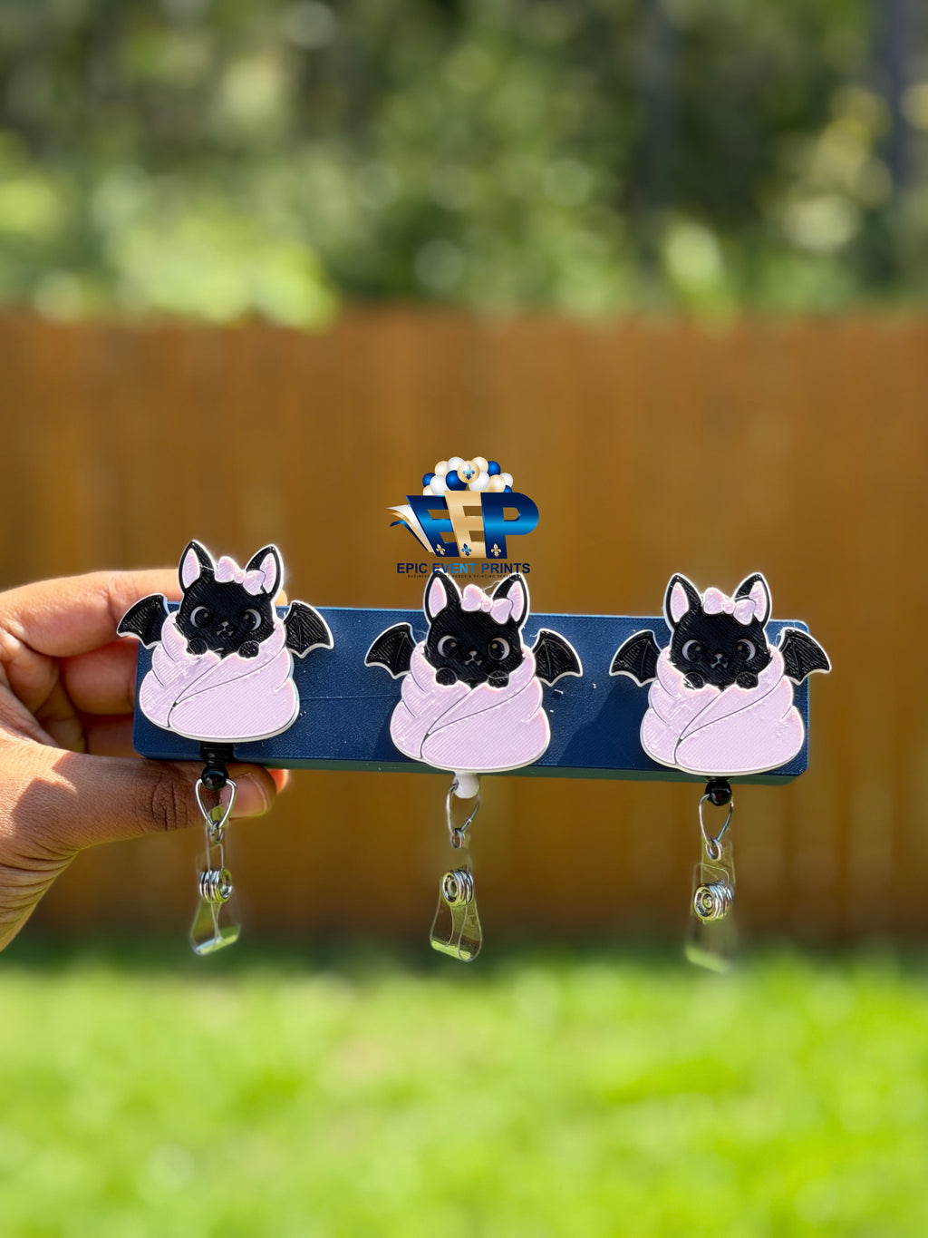 Black bat badge reels with pink bows and pale pink wraps on retractable clips