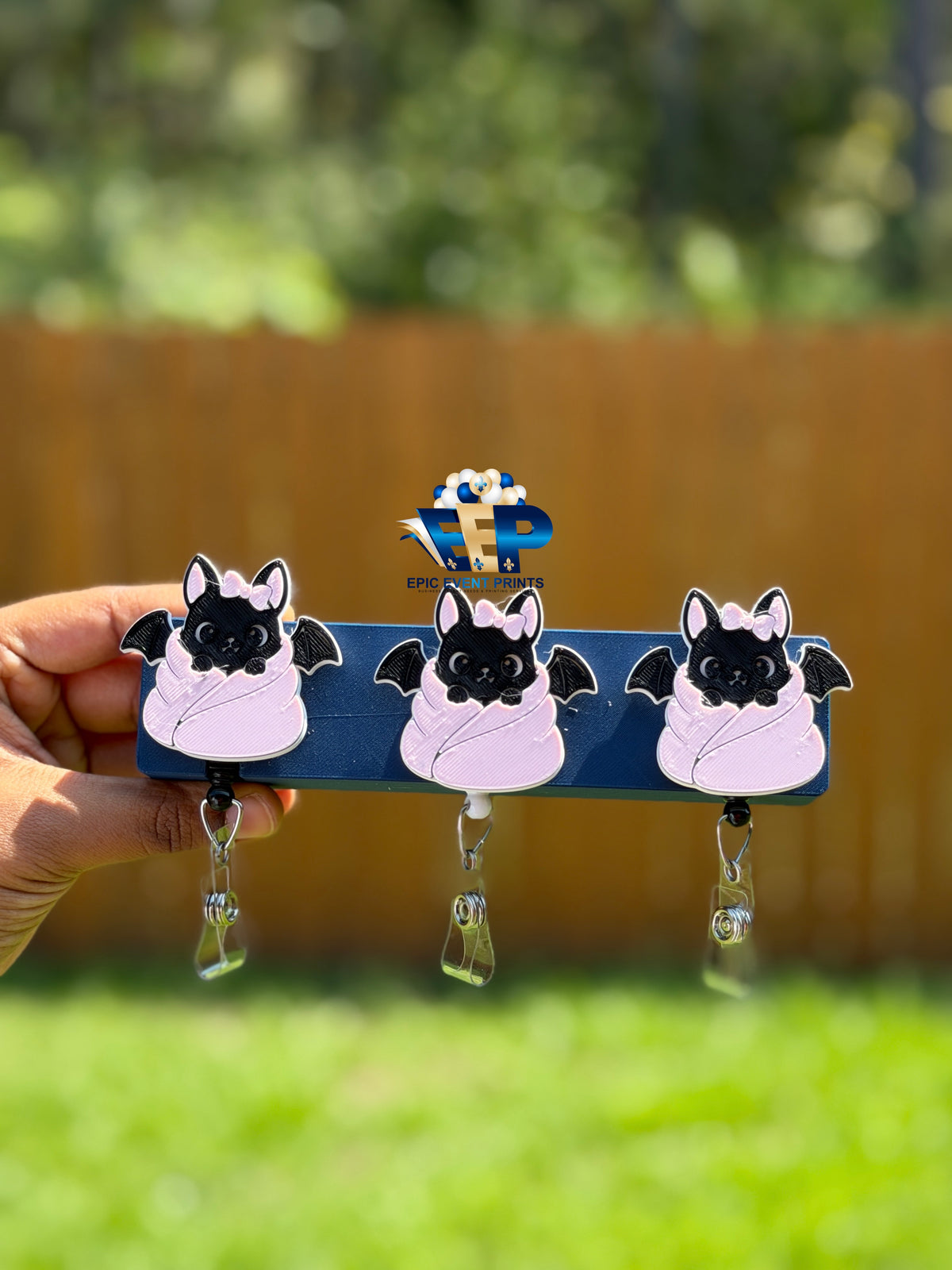 Black bat badge reels with pink bows and pale pink wraps on retractable clips