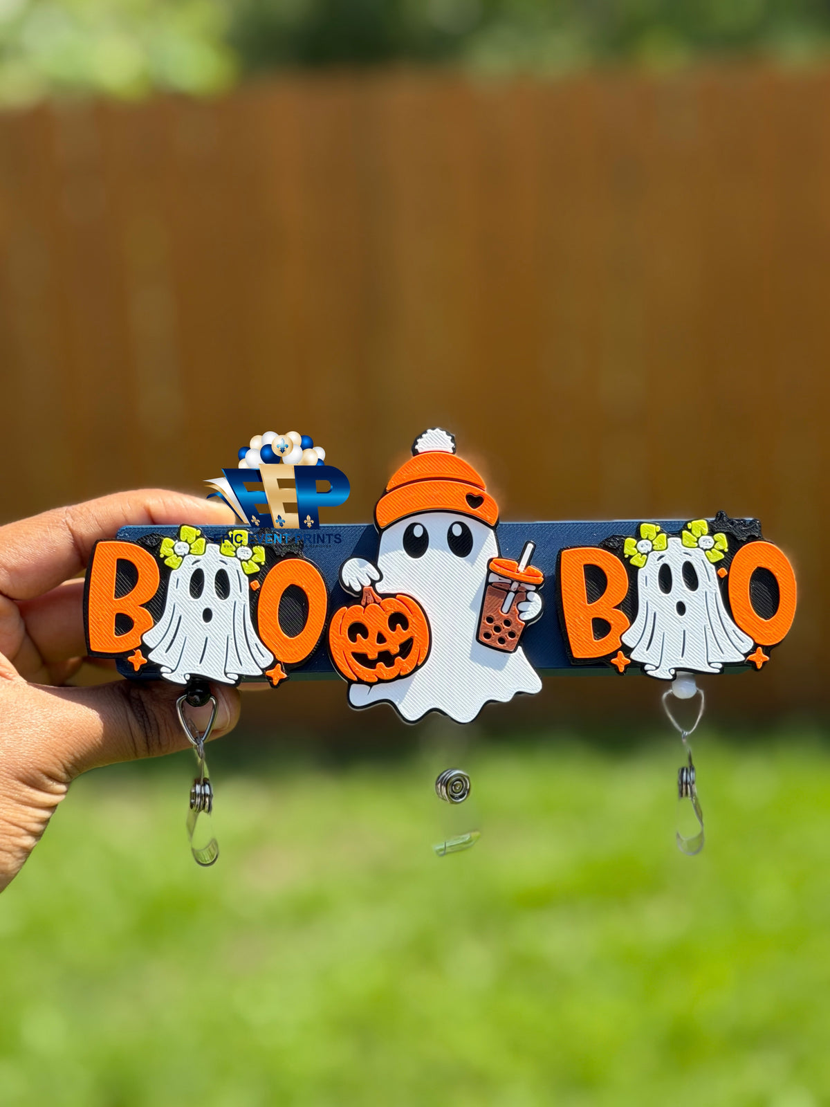 Two BOO ghost badge reels on either side of a separate pumpkin and boba ghost design