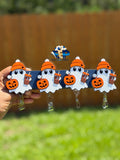 Four white ghost badge reels wearing orange beanies and holding pumpkins and boba drinks